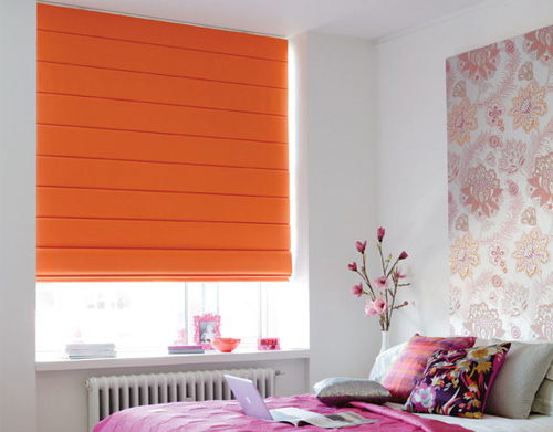 Bright orange roman blinds in a colourful bedroom