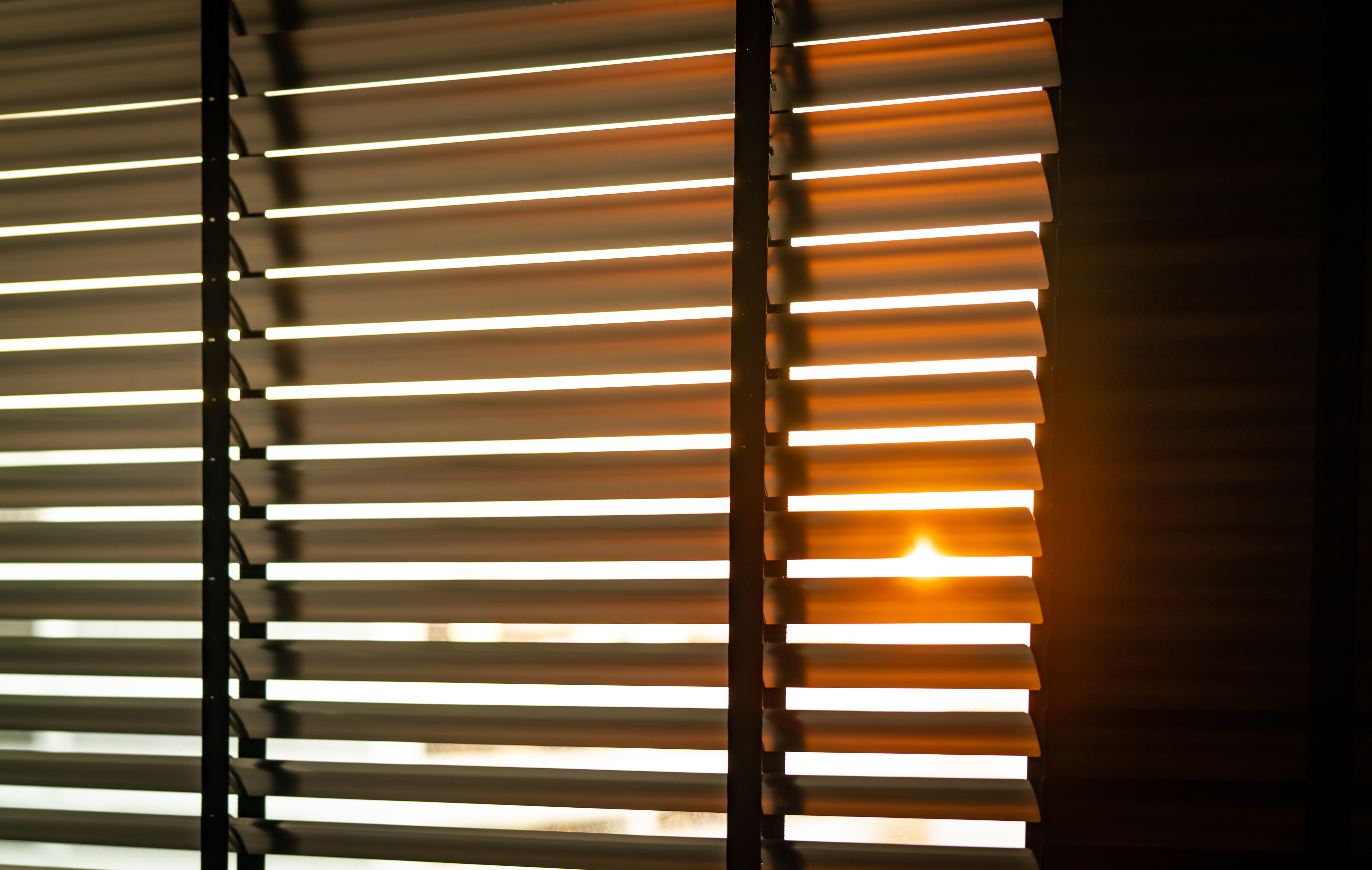 Opened venetian plastic blinds with sunlight in the morning. White plastic window with blinds. Interior design of living room with window horizontal blinds. Window slatted shades made of plastic.