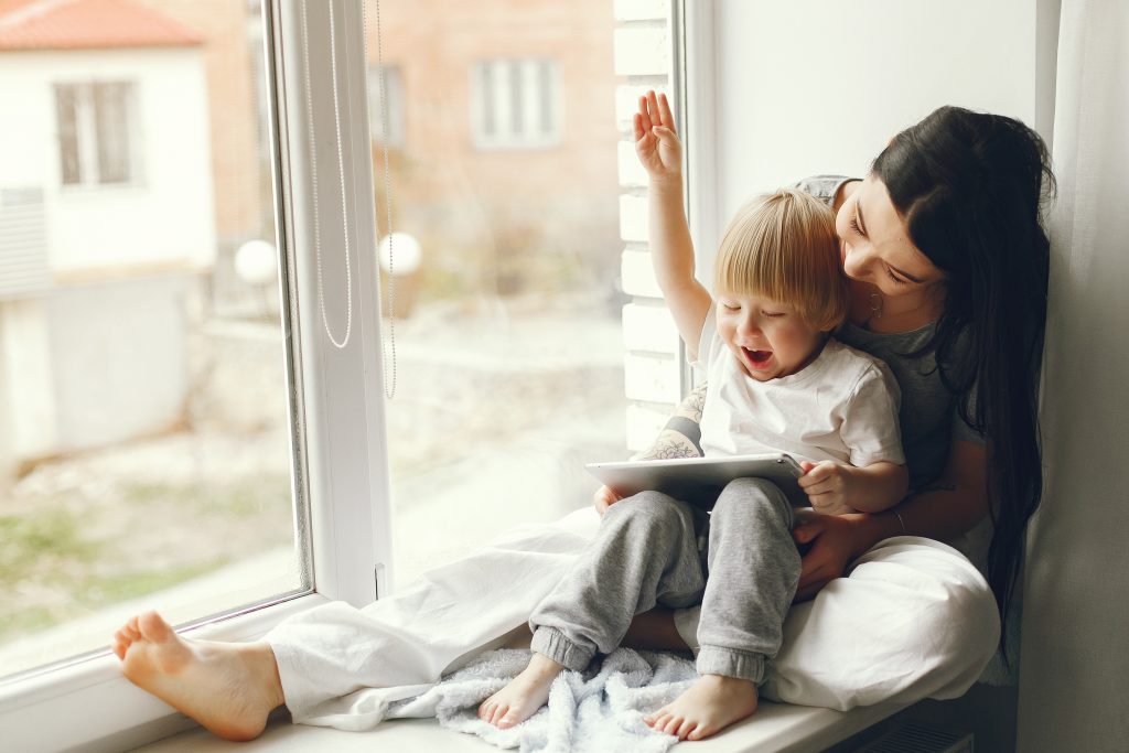 Beautiful woman with child. Woman in a gray t-shirt. Family sitting on a windowsill.