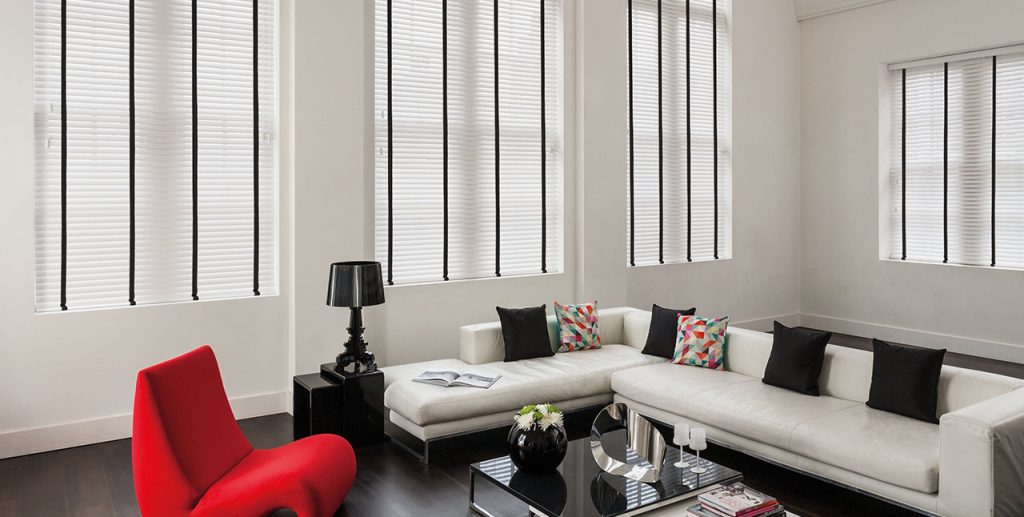 White and black venetian blinds in a white lounge with statement pieces of furniture