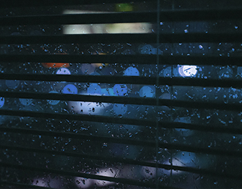 Dark Venetian blinds snapshot with rain in the background