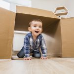 Little boy playing with a cardboard box at home