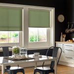 Window blinds Coventry. Green roller blinds in kitchen window. Dark walls and dining table.