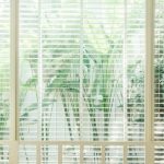 Made to measure Venetian blinds coventry. White Venetian blinds looking out onto a garden with plants.