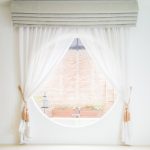 Grey fitted blinds and curtains decorating a small round window.